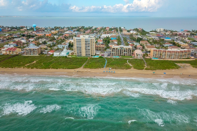 Aerial view of the shores of South Padre Island, a popular snowbird destination in Texas, with resort buildings and beach town neighborhoods visible in the background.