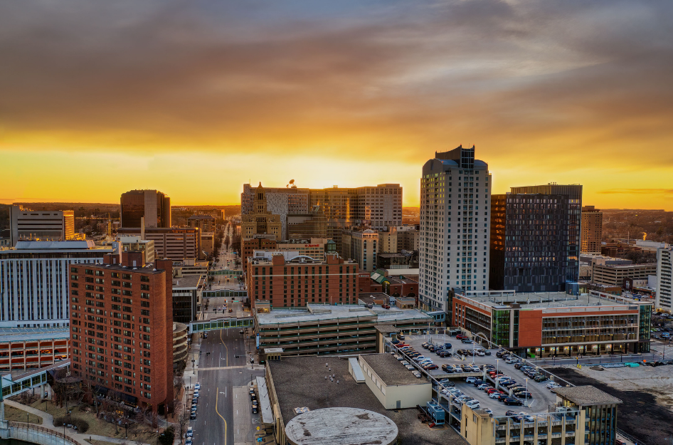 An aerial image of downtown Omaha, NE as the sun sets in the background.