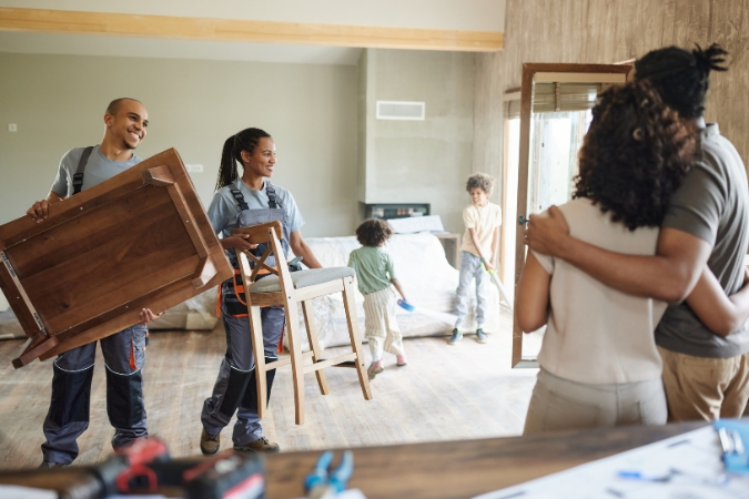 A couple is directing hourly movers as they carry furniture out of their house — just one step on their moving day checklist.