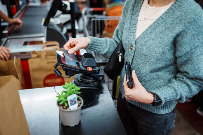 Close-up of a woman paying for her groceries with a credit card.