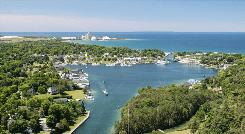 Beautiful forests and waterfront homes on the banks of Round Lake in Charlevoix, Michigan. It’s summer and everything is green and sunny.