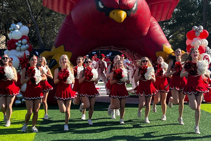 Cheerleaders run out onto the field during the Little League Opening Ceremonies in Bellaire — one of the best cities near Houston, TX.