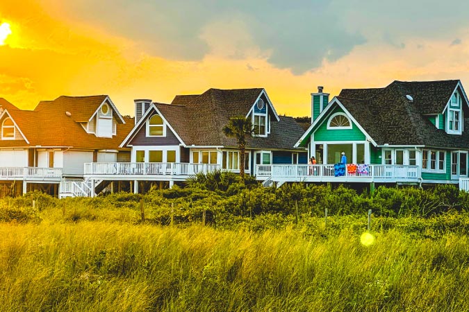The sun sets behind three stilted beach houses on Isle of Palms in South Carolina — a popular destination for those living in Charleston, SC.