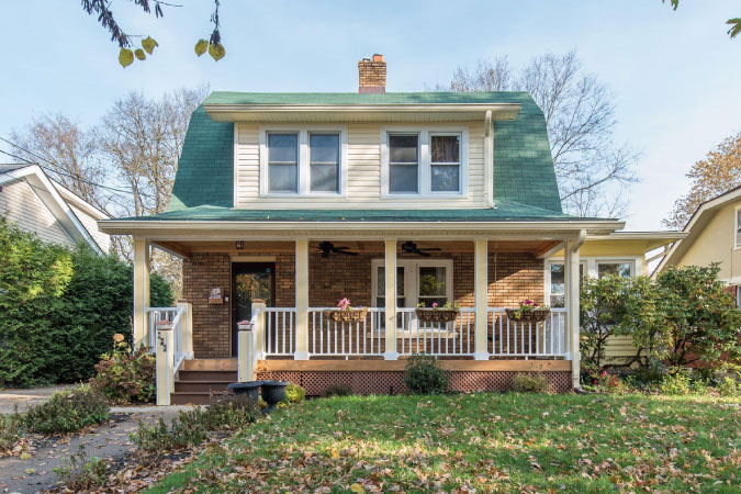 A bungalow in Hollywood — one of the best neighborhoods in Lexington, KY — featuring a covered porch, central chimney, and green roof.