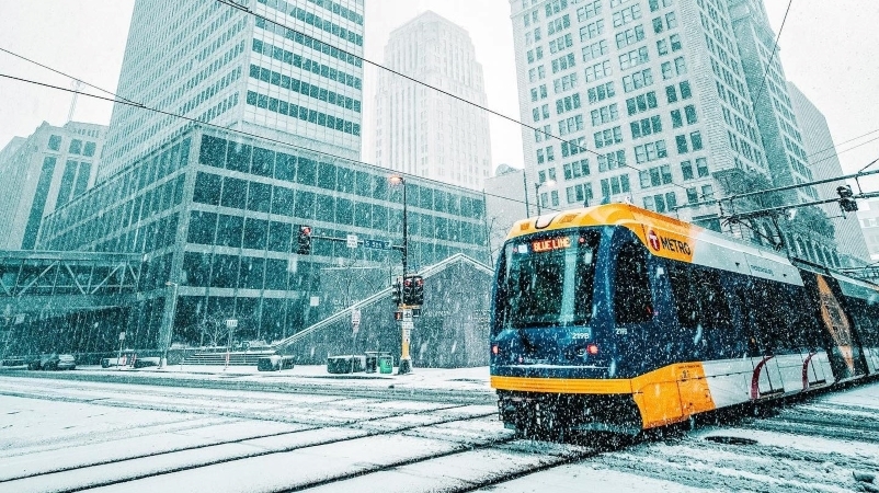 A METRO light rail train travels along snow-covered city streets as a winter storm blows through Minneapolis. 