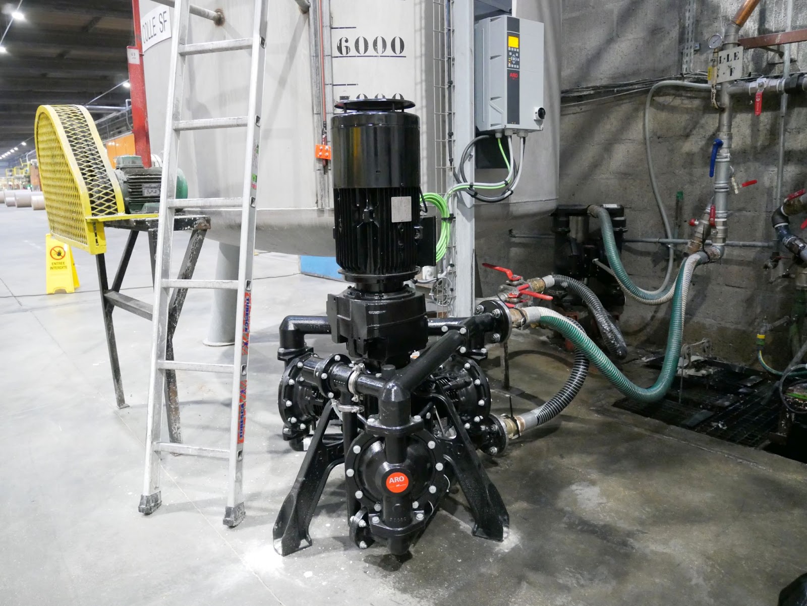 Industrial machinery with pipes, a motor, and a large tank
