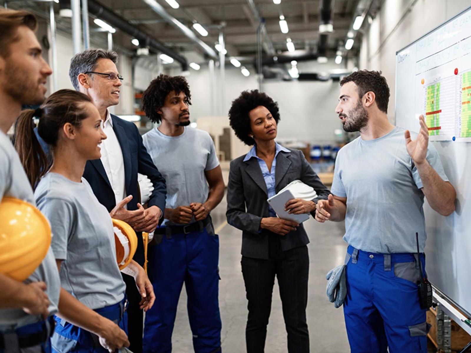 A group of people talking in front of a white board