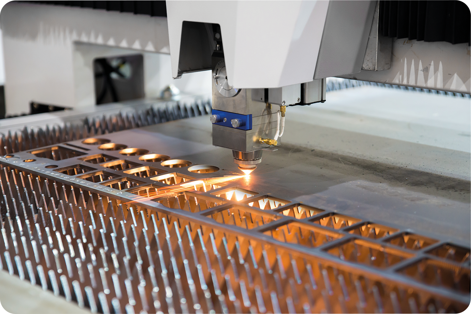 Industrial laser cutting production line with stacked metal sheets and finished components prepared for manufacturing.