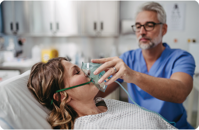 Healthcare professional administering oxygen through mask to patient in hospital bed during respiratory treatment