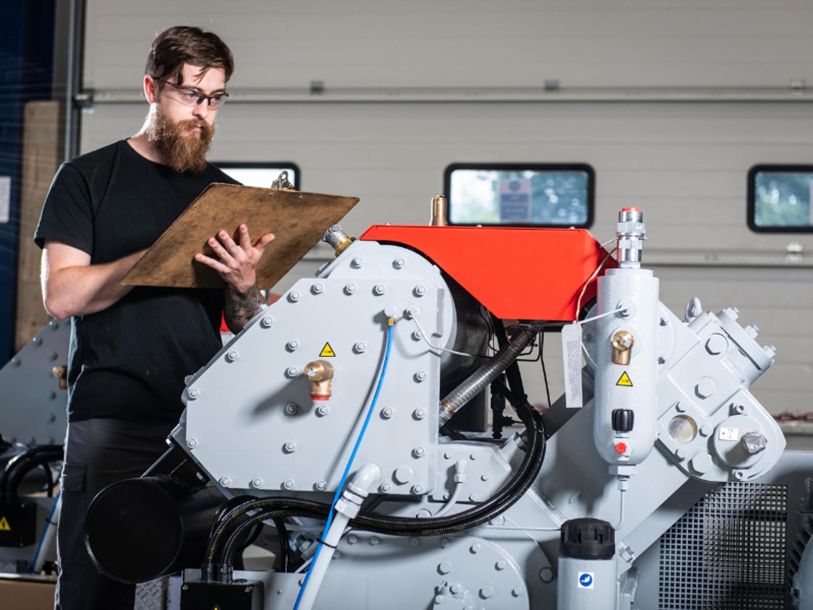 A person standing next to a Belliss & Morcom machine performance evaluation