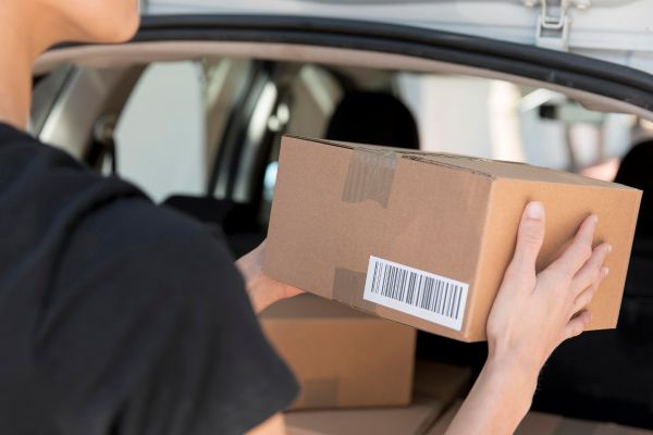 Man holding a box with a barcode label on it.