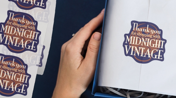 Gift box with item wrapped in tissue paper. Closed with sticker saying "Thank you for shopping Midnight Vintage"