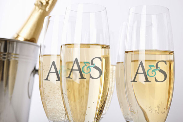 A bucket containing a champagne bottle. Next to the bucket we have five glasses filled with champagne. All glasses have the same logo printed on them.
