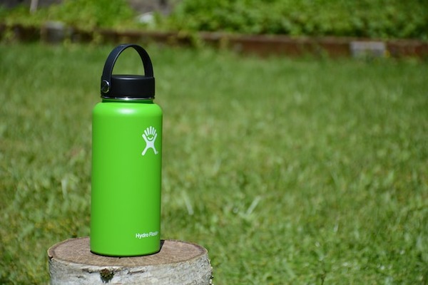 Green hydro flask on a stump.