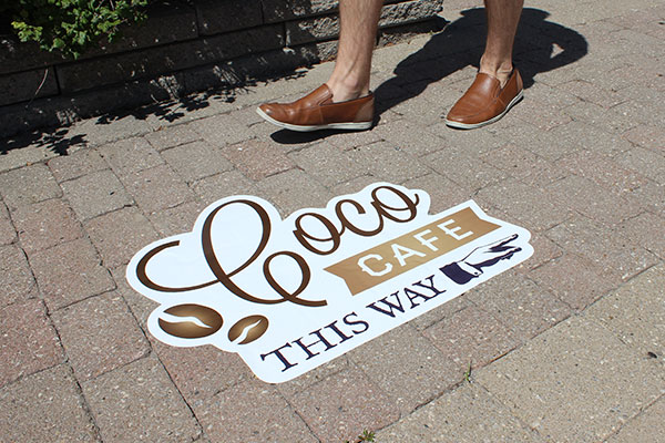 Branded street decal pointing to a coffee shop
