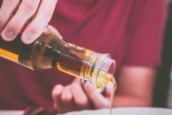 Man holding a clear glass bottle of oil