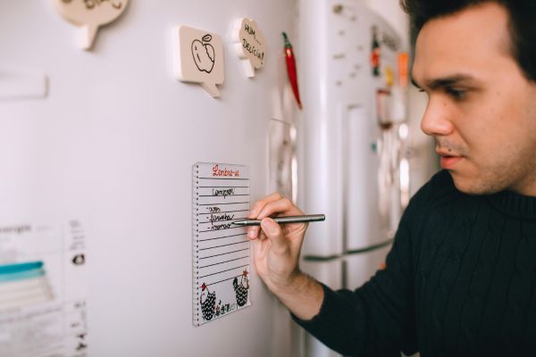A man writing on a fridge magnet