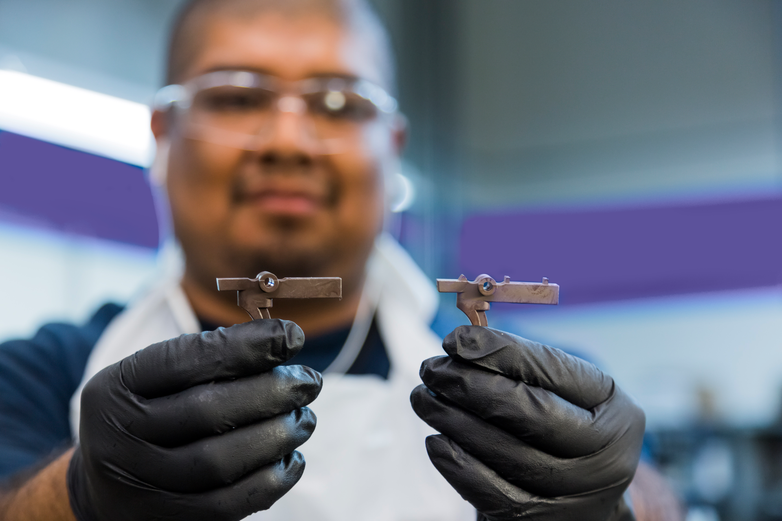 Employee holding two complete MIM parts