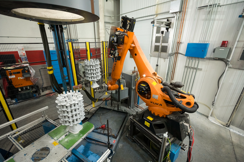 Robotic arm moving an investment casting mold
