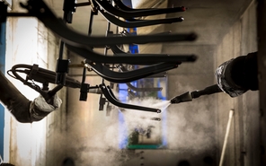 Investment casted parts being sprayed with a surface finish