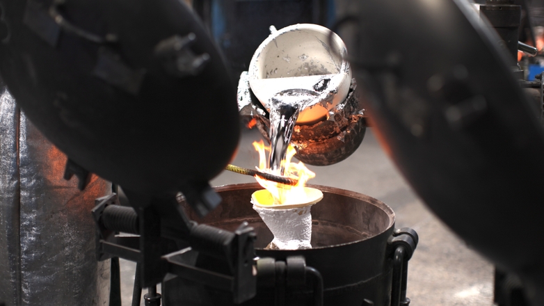 Molten metal pouring into an investment casting mold