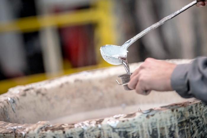 Employee ladling metal into a cup