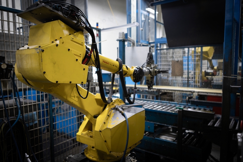 Yellow robot arm moving in a cell