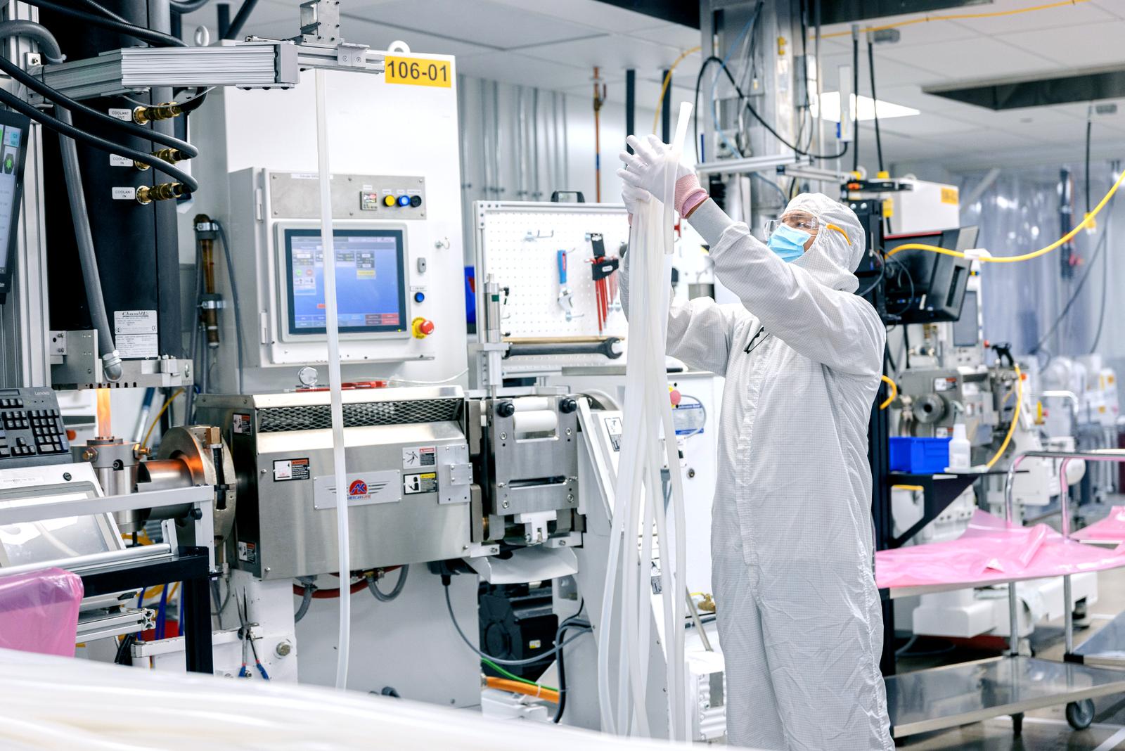 : Flexan technician operating a medical extrusion manufacturing line in a controlled cleanroom environment for precision tubing and component production.